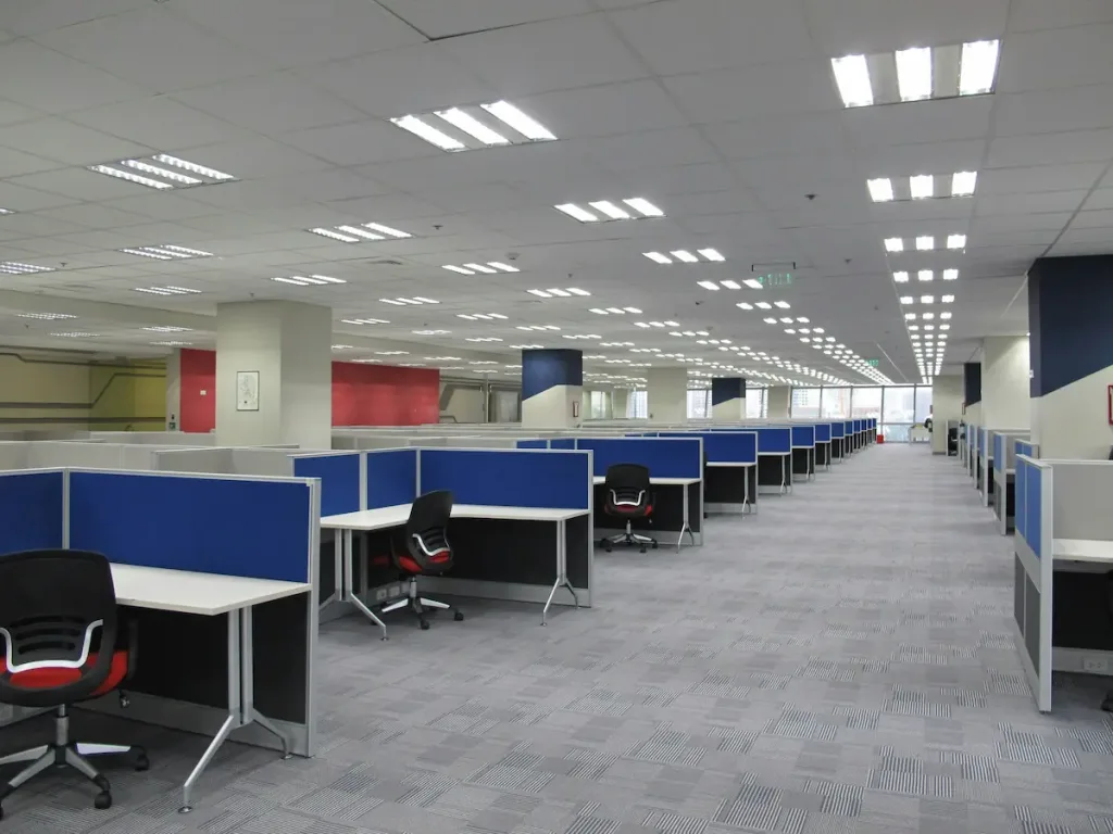 Interior kantor konvensional dengan banyak partisi, menunjukkan ruang kerja yang belum diisi